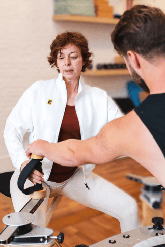 De yogadocent helpt haar student met GYROTONIC apparatuur